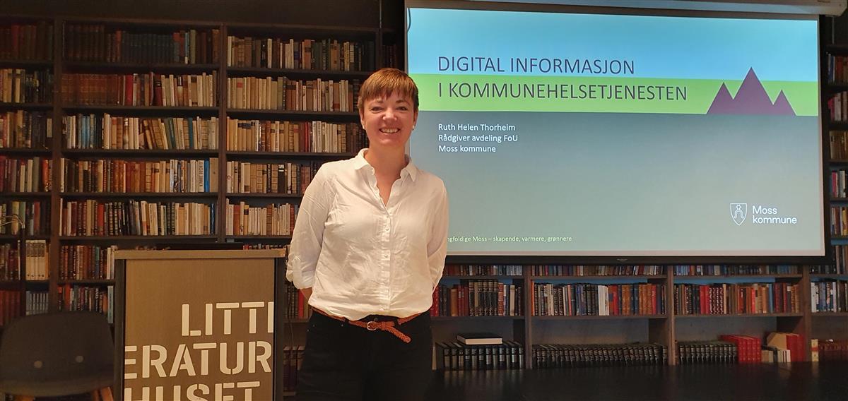 Ruth Helen Thorheim står foran skjermen med sin presentasjon på Litteraturhuset i Fredrikstad - Klikk for stort bilde